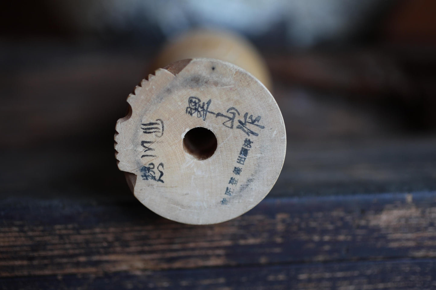 a wooden object with a carved design and some text or symbols on it, resting on a wooden surface.