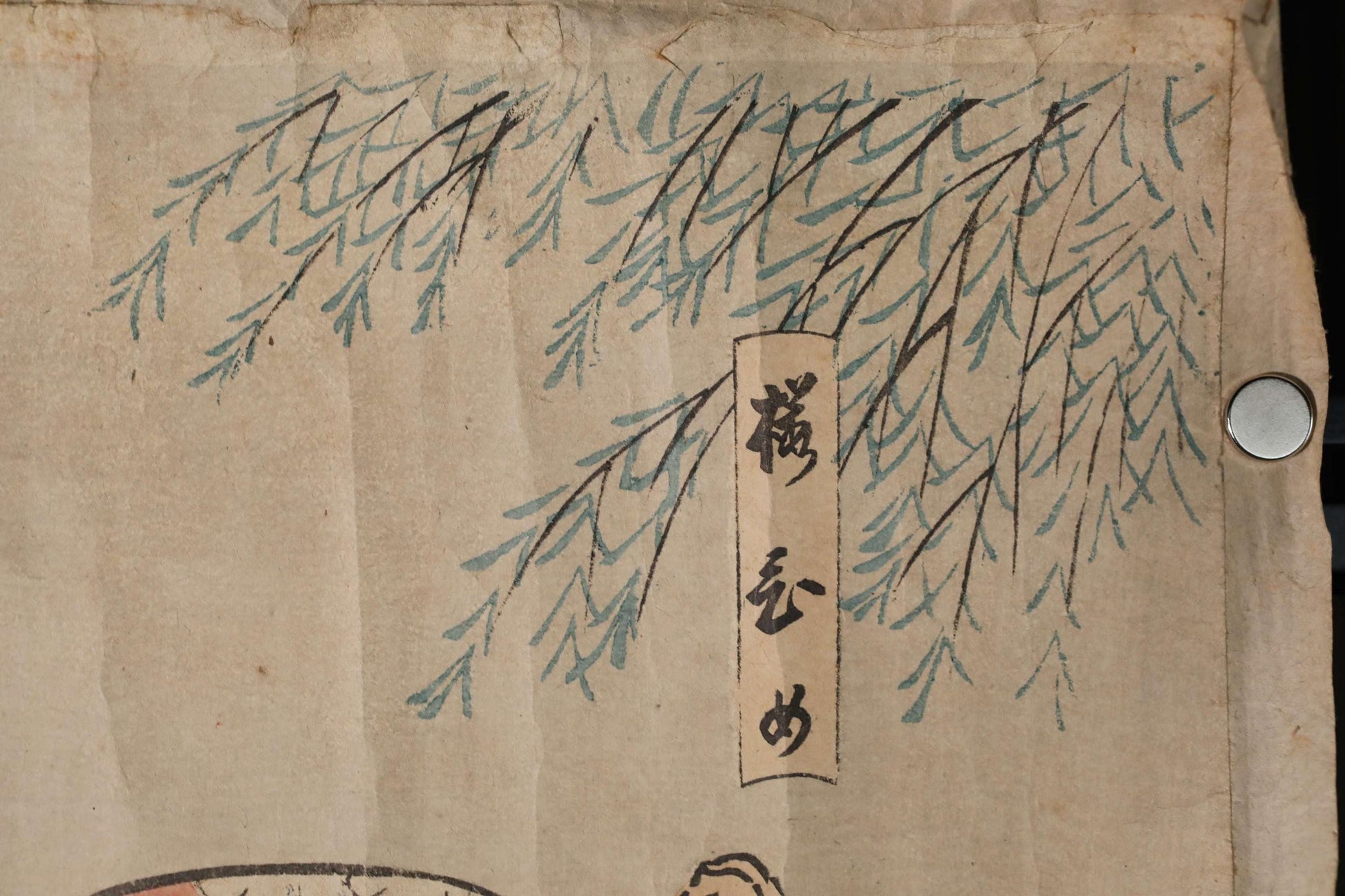 a close-up view of a piece of paper with a drawing of a tree branch and some Japanese text.