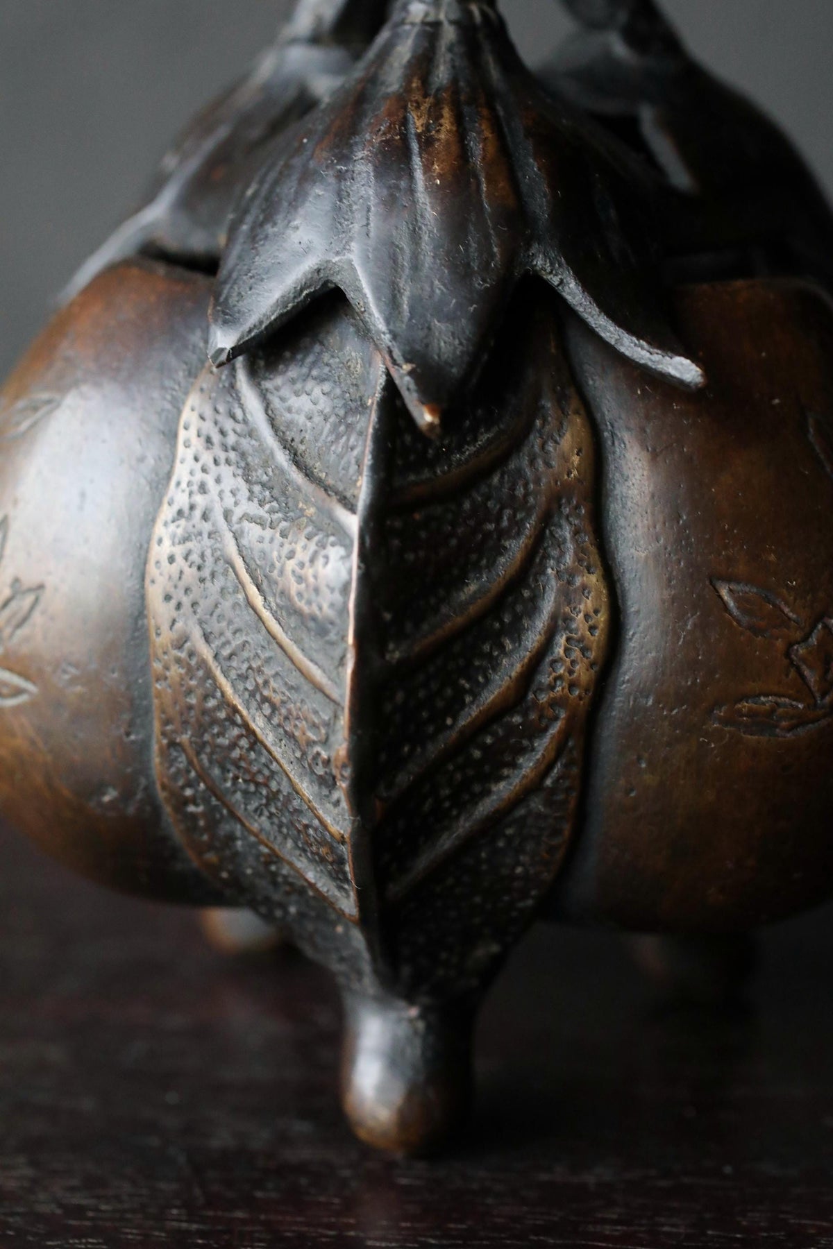 A close-up view of a bronze incense burner with a leaf-like design on the front.