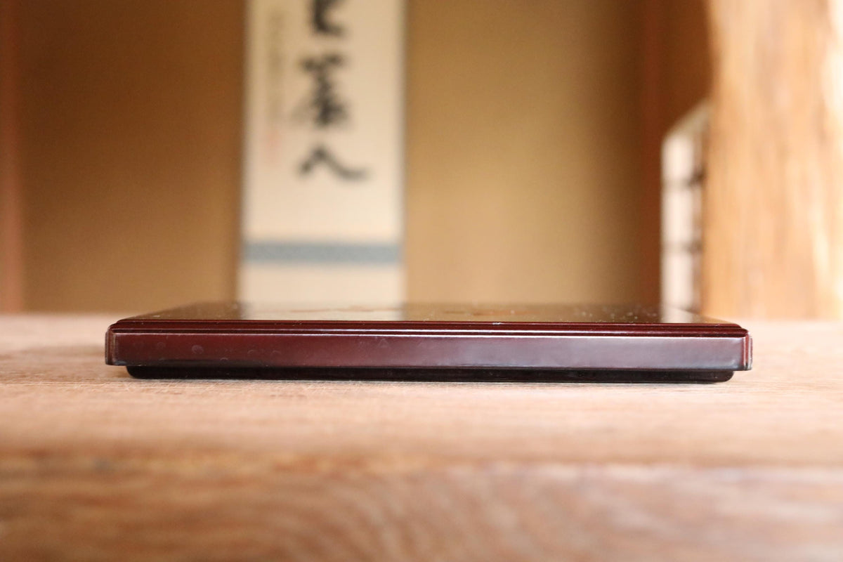 A wooden surface with a dark-colored rectangular object placed on it.