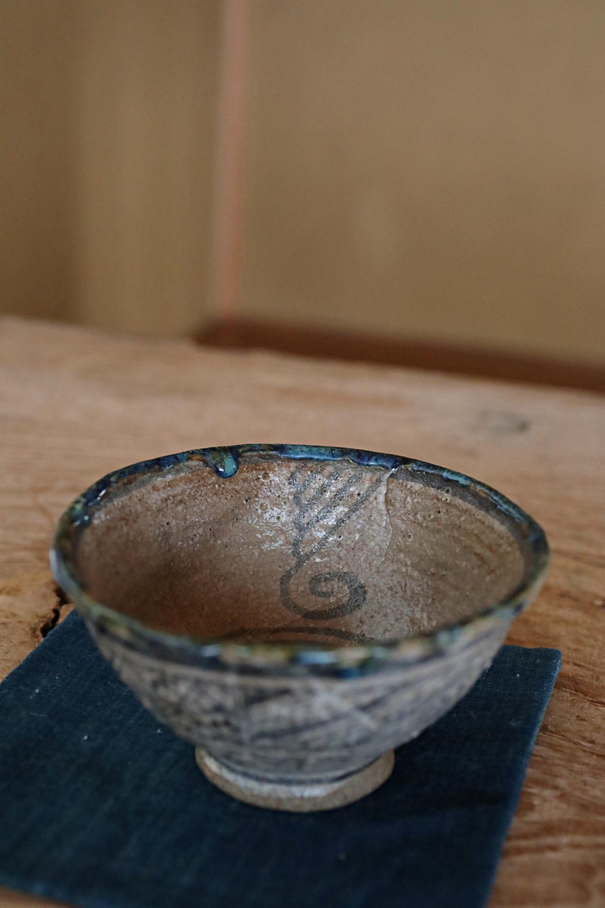 A ceramic bowl with a blue rim sits on a blue cloth on a wooden table.