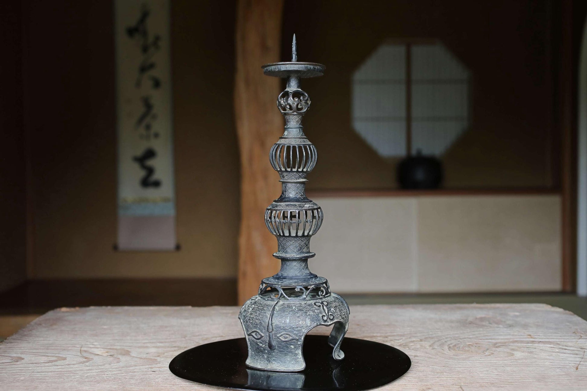 a decorative metal candlestick with a tall, ornate design on a wooden surface.