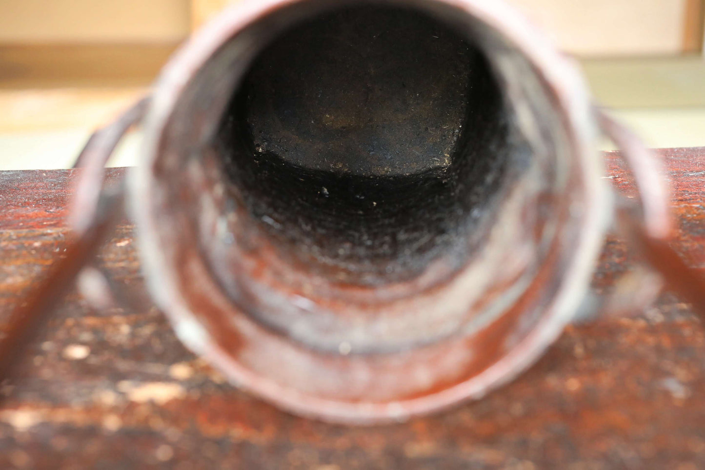 a close-up view of a rusted metal pipe or tube, with a dark, weathered surface.