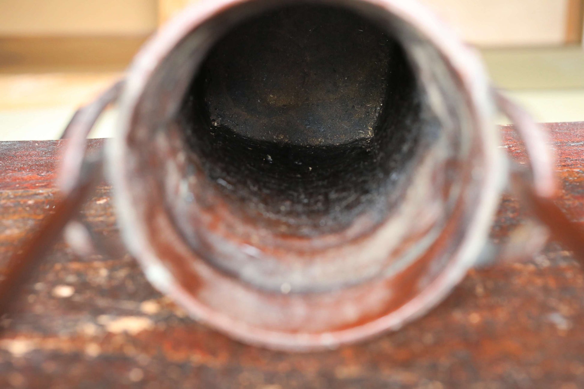 a close-up view of a rusted metal pipe or tube, with a dark, weathered surface.
