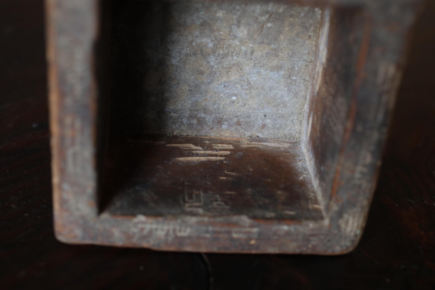 a close-up view of a wooden object, possibly a box or a container, with visible signs of wear and tear, such as rust and peeling paint.