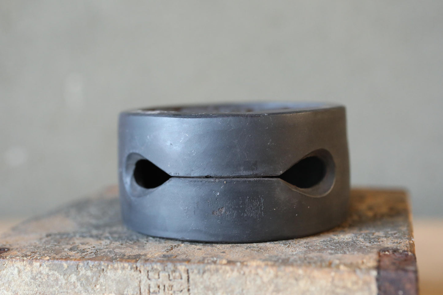 A close-up image of a black metal object with two circular holes, sitting on a wooden surface.