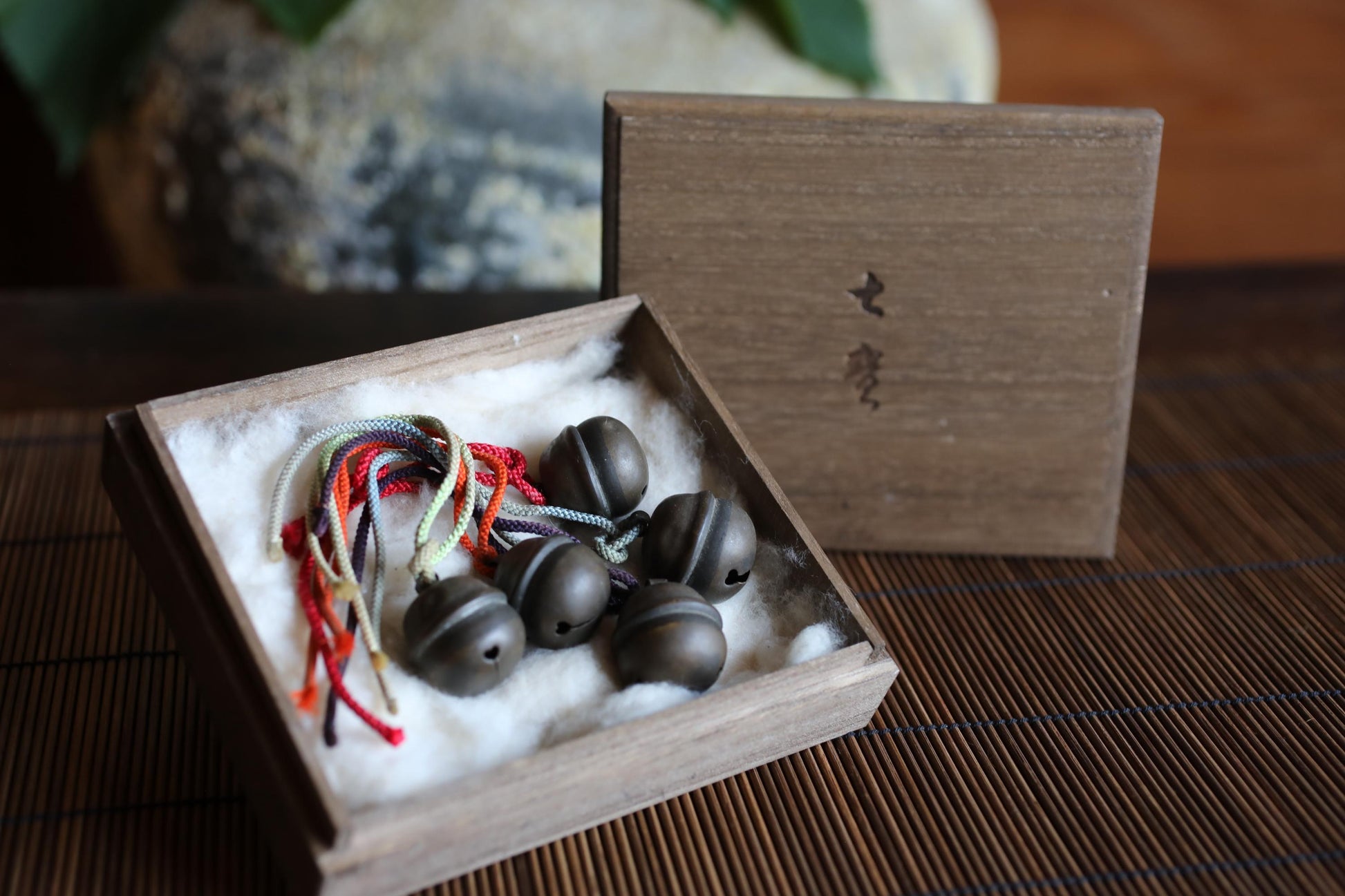 A wooden box containing several small, round bells, possibly made of metal, placed on a wooden surface.