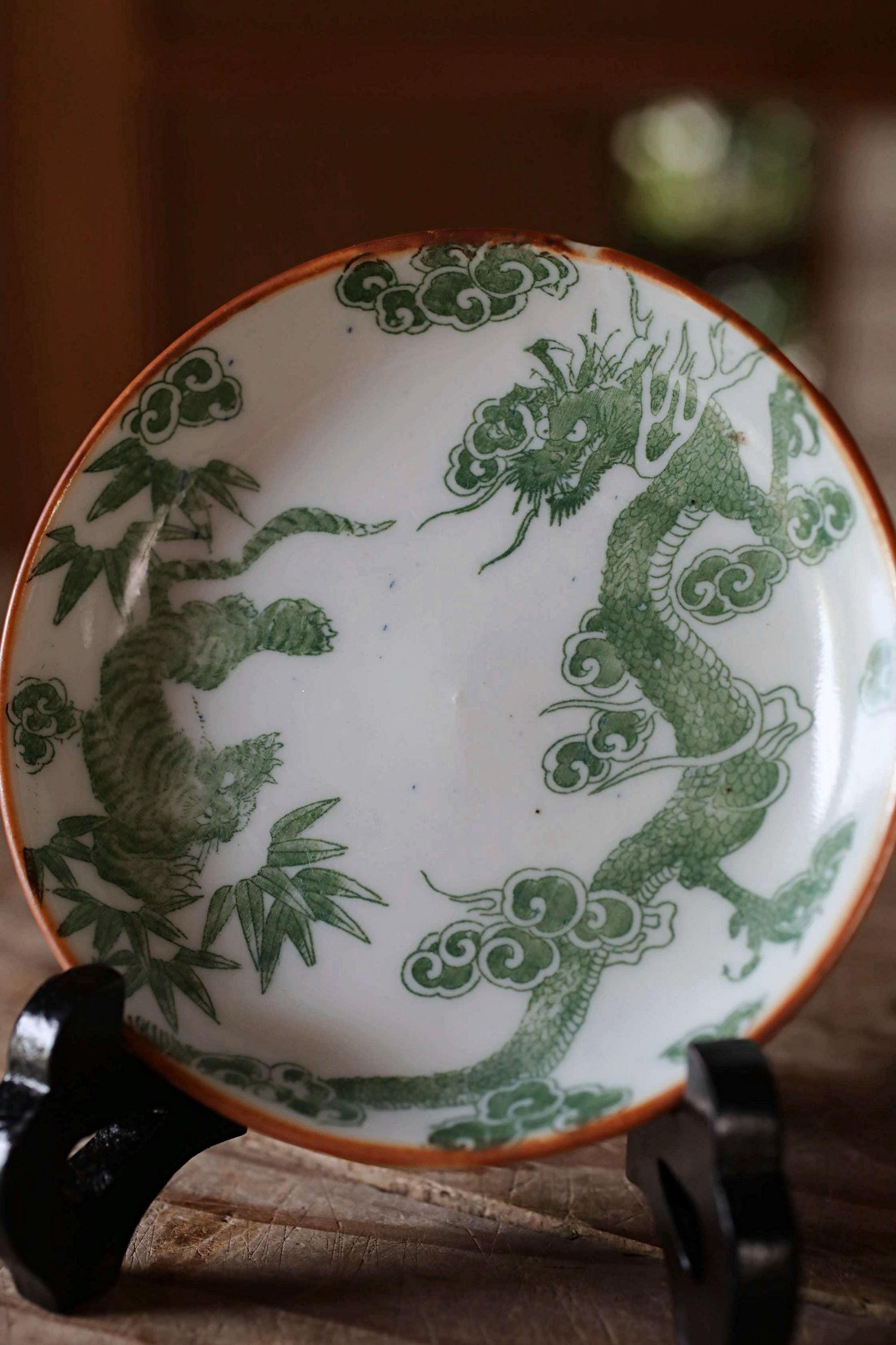 A decorative plate with a dragon design on it, placed on a wooden surface.