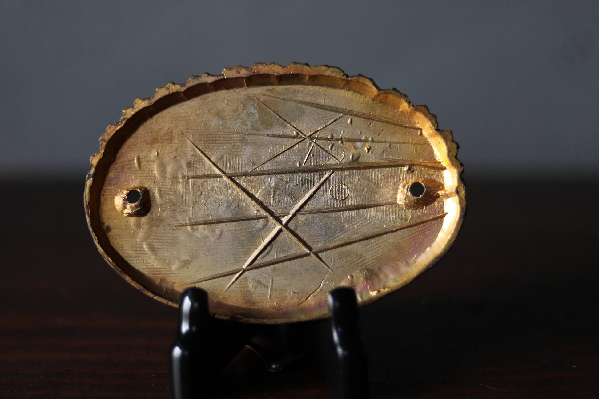 a close-up view of a golden oval-shaped object with a pattern of lines and dots on its surface, which appears to be a decorative piece.