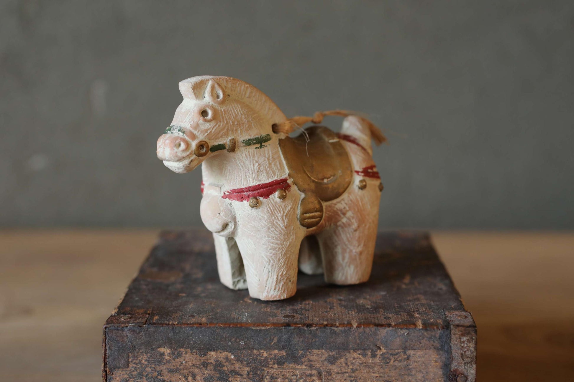 A small, white wooden figurine of a horse is sitting on a wooden surface.