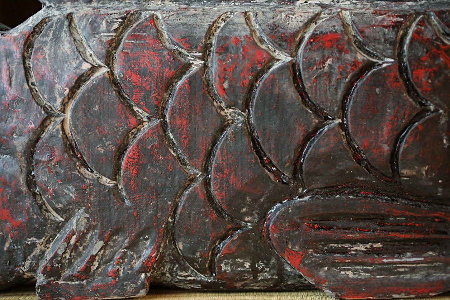a close-up view of a textured surface with a pattern of red and black colors, resembling a fish or a decorative design.