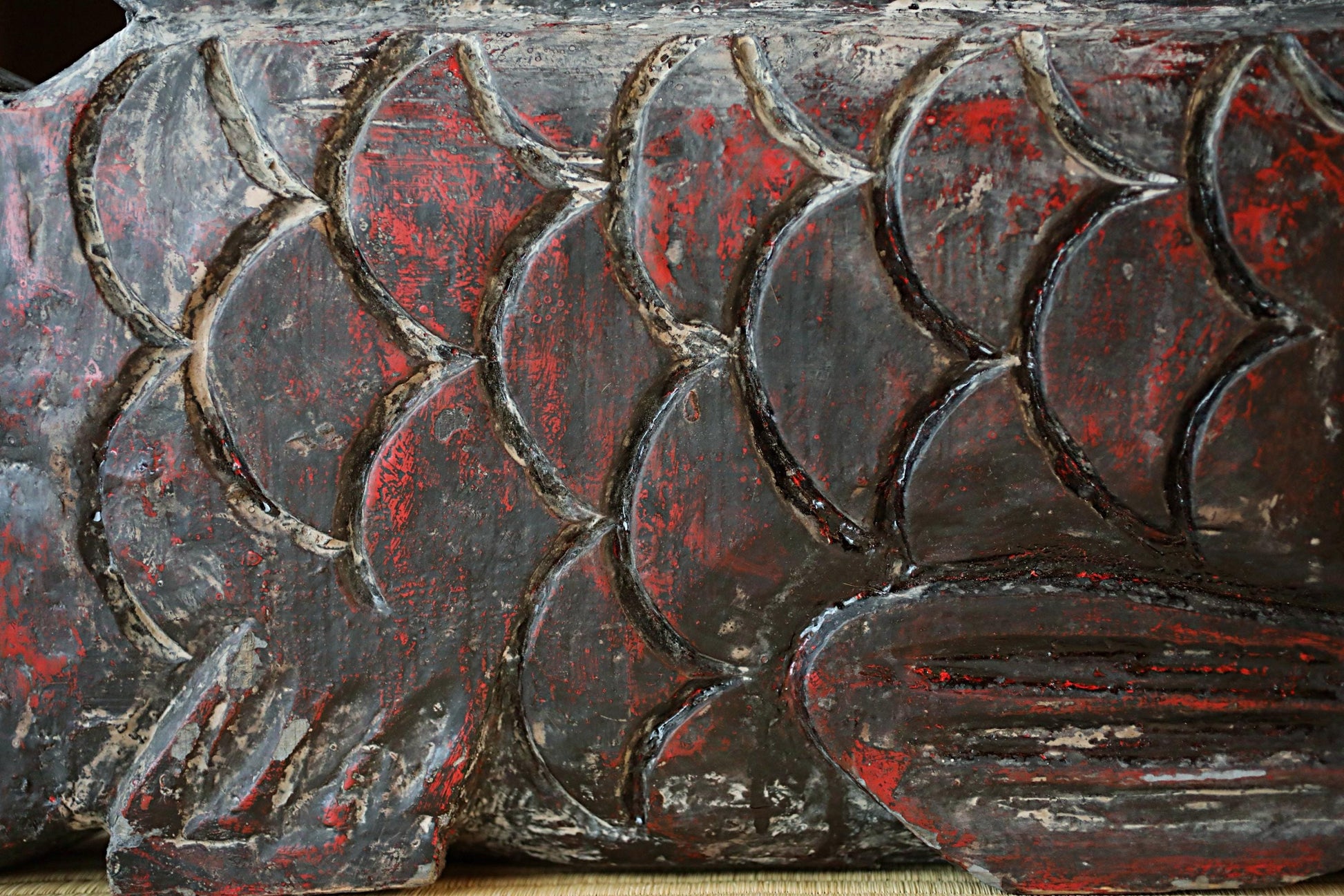 a close-up view of a textured surface with a pattern of red and black colors, resembling a fish or a decorative design.