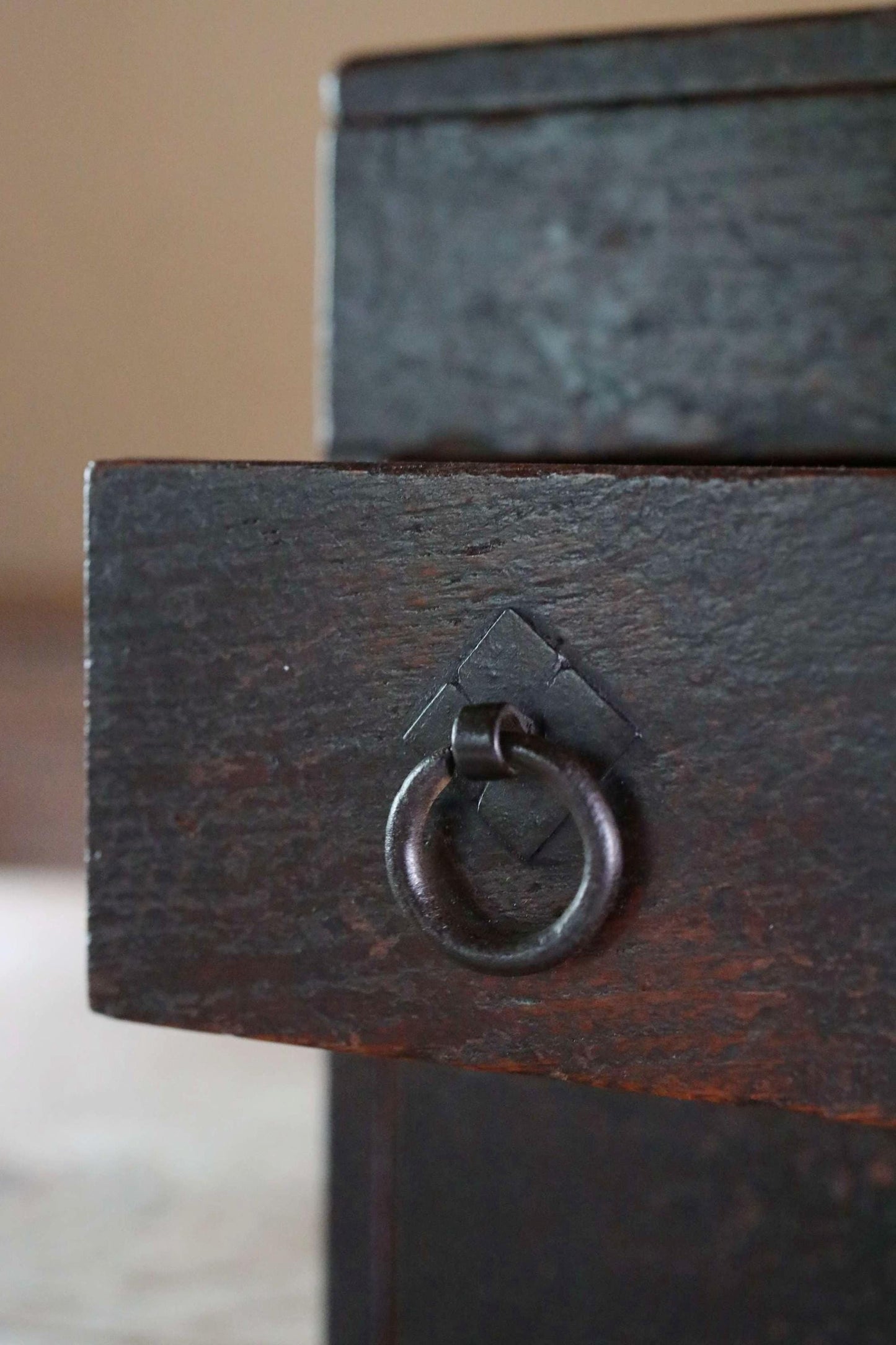 a close-up view of a dark wooden drawer with a metal ring on the handle.