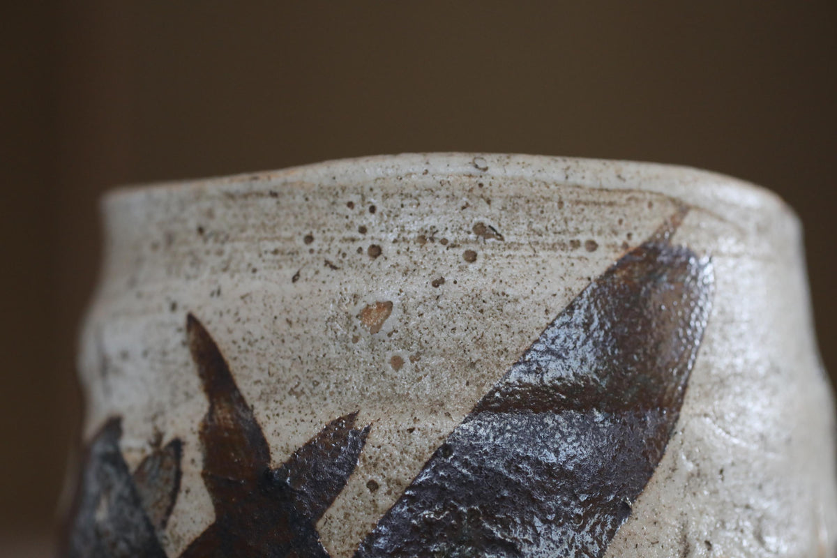 A close-up view of a ceramic vase with a black and white design, featuring a textured surface with small holes or speckles.