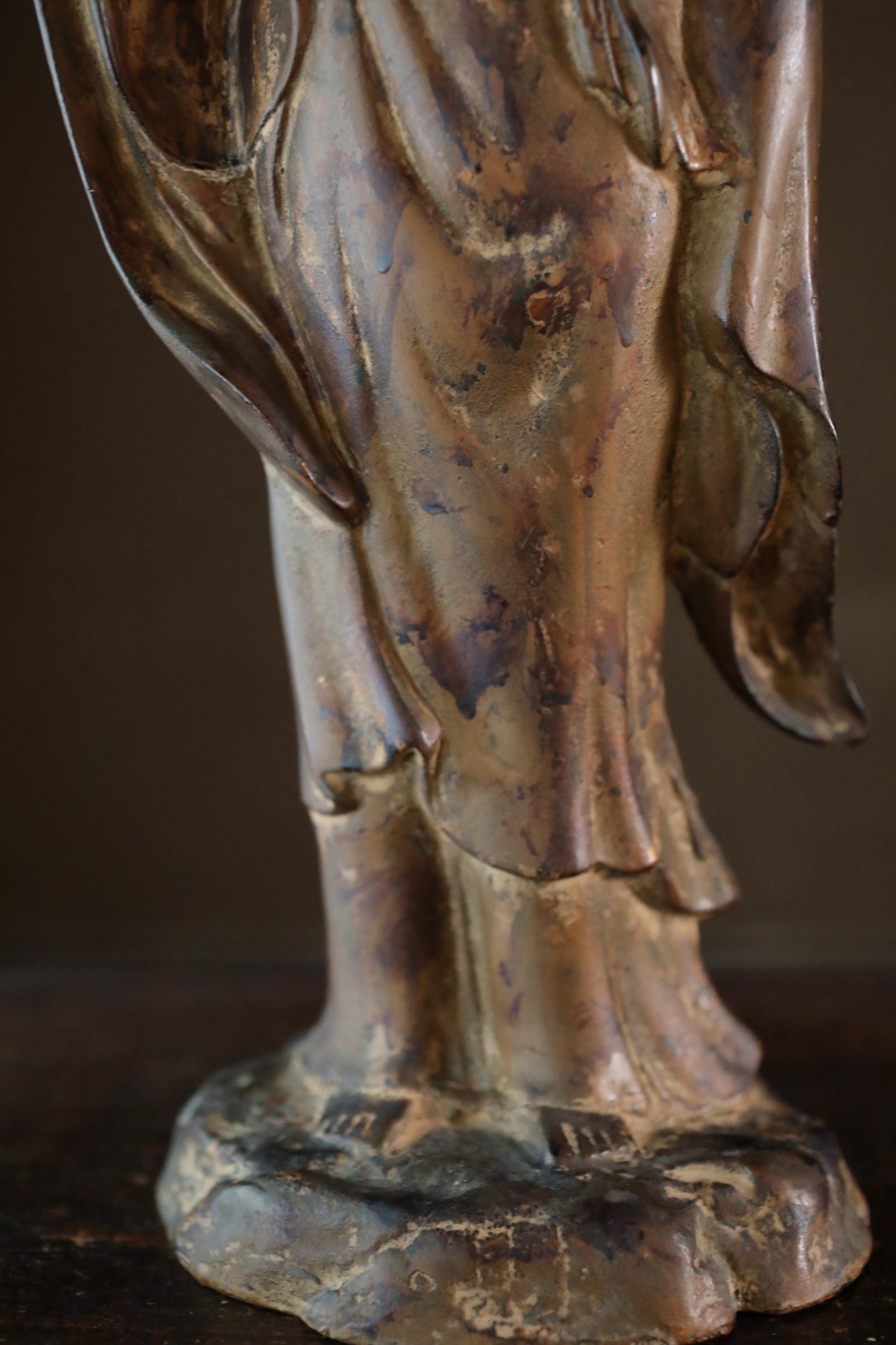 A close-up view of a bronze statue depicting a figure with flowing robes and a flowing headdress.