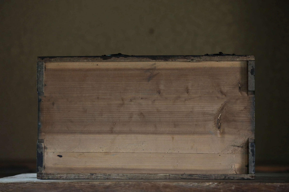 a wooden box with a weathered, aged appearance, sitting on a wooden surface.