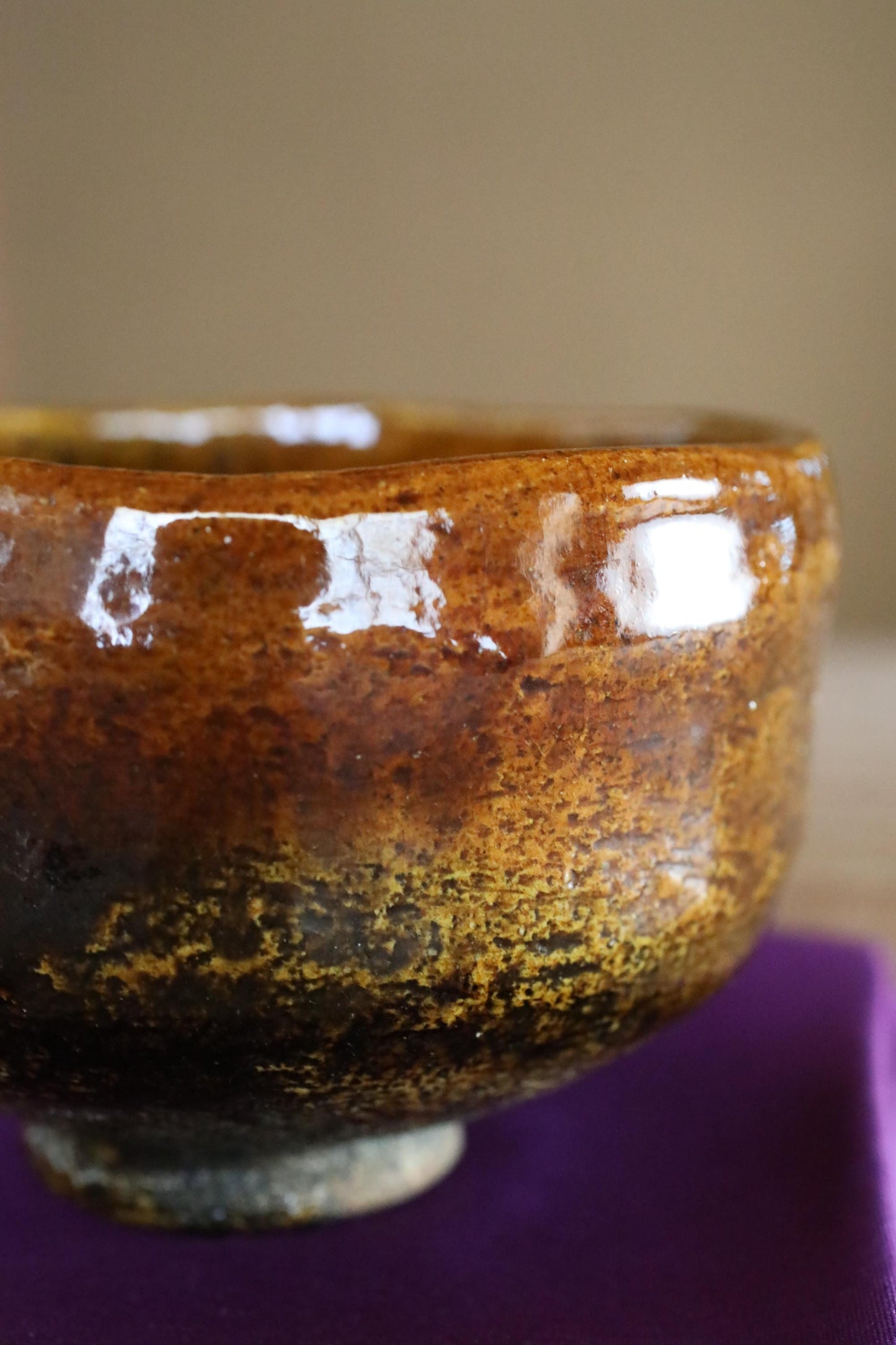 A close-up view of a ceramic bowl with a brown and black color scheme, featuring a textured surface and a reflective quality.