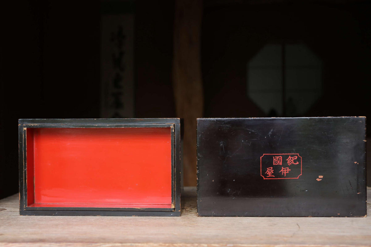 a red and black box with a red interior, placed on a wooden surface.