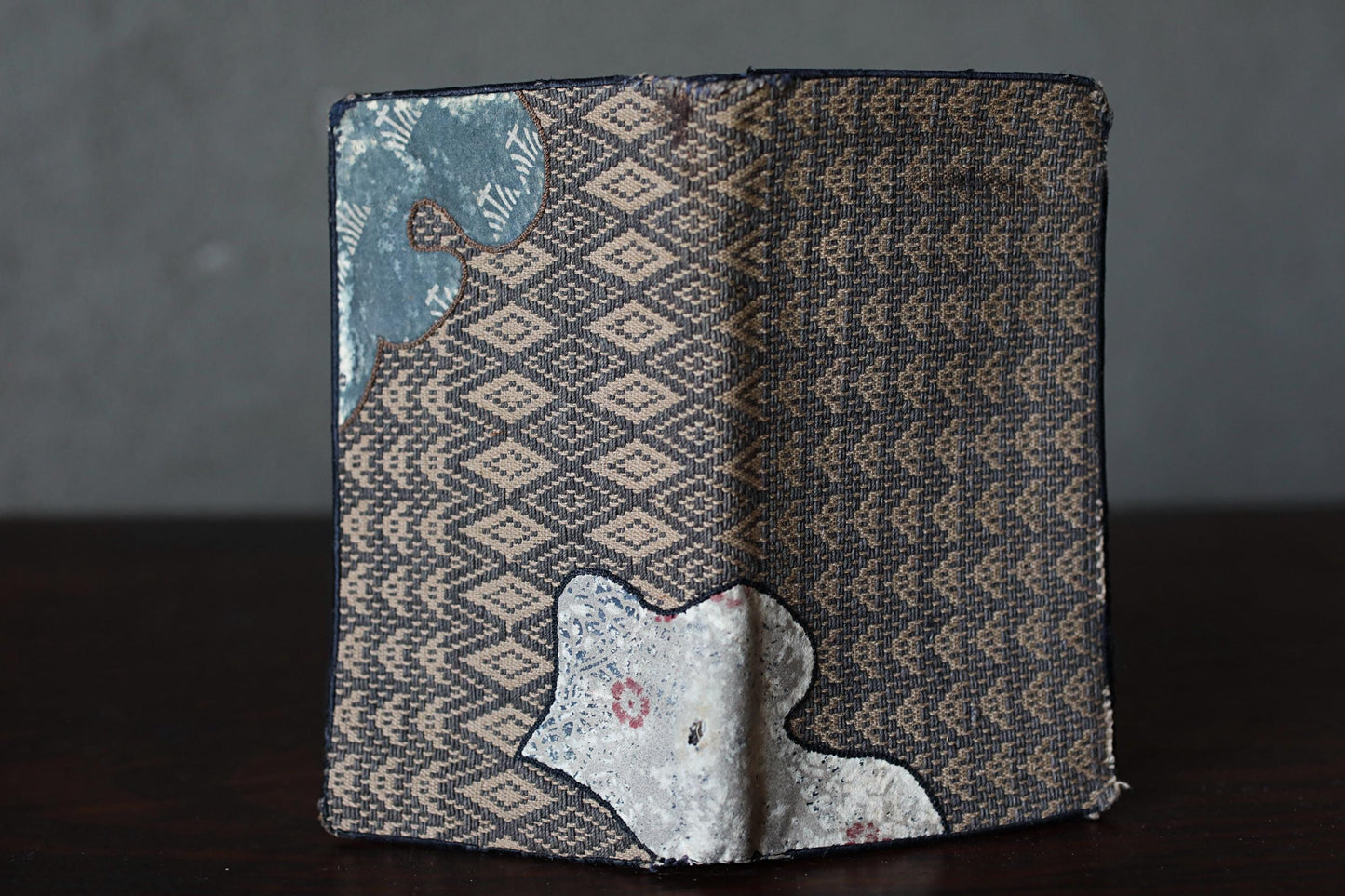 an open book with a patterned cover, sitting on a dark surface.