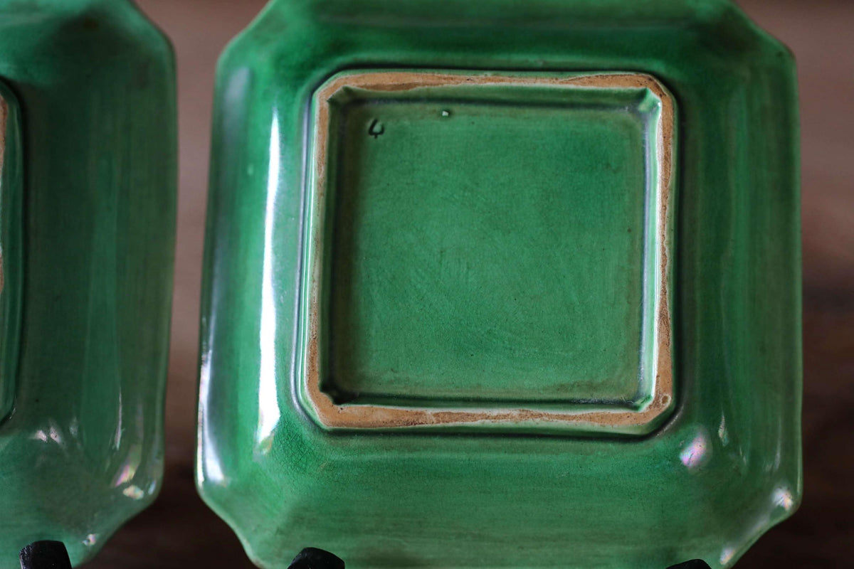 a close-up view of two green ceramic plates with a square design.