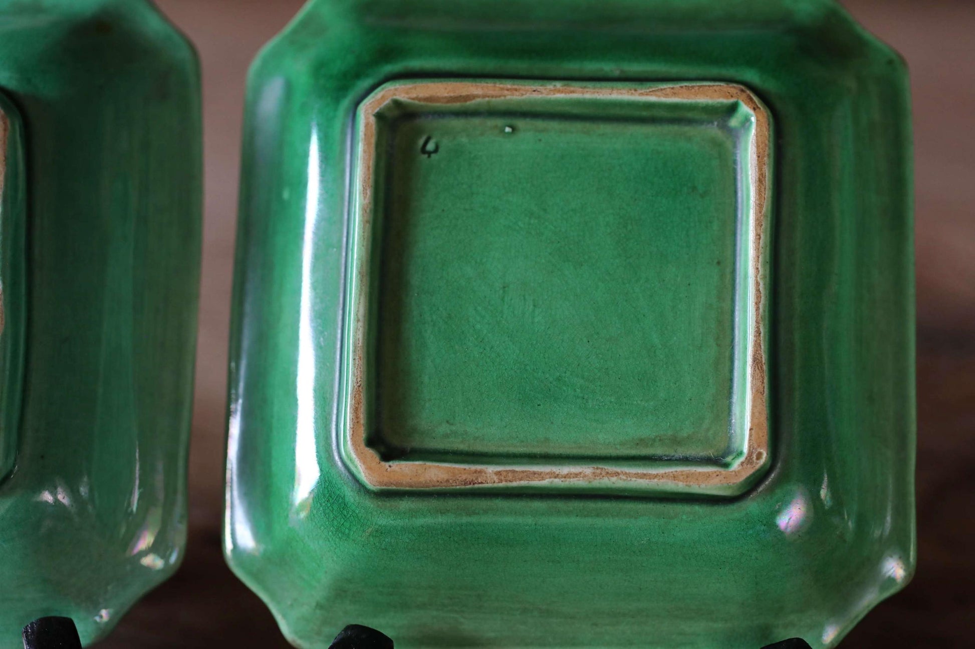 a close-up view of two green ceramic plates with a square design.