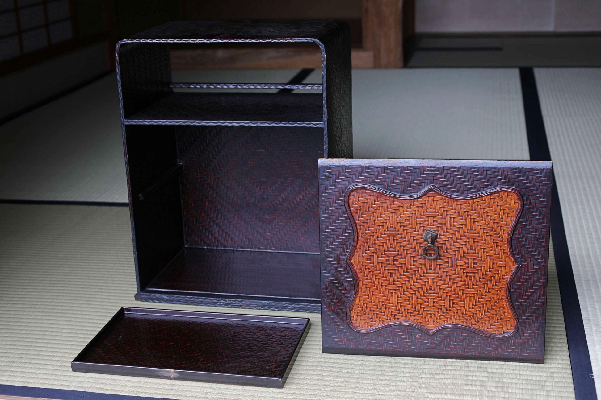 a wooden box with a lid and a tray, placed on a tatami mat.