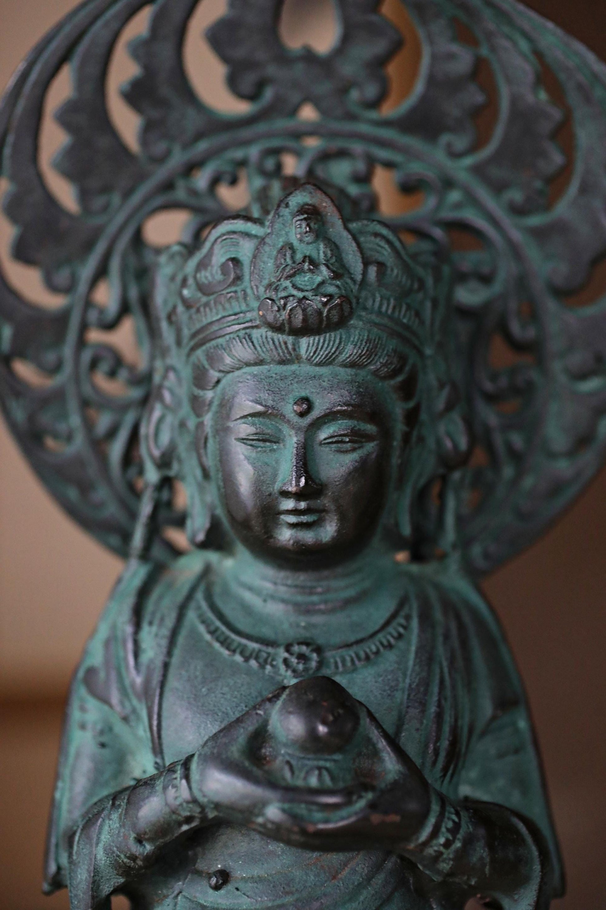 A bronze statue of a deity holding a ball, with intricate designs and patterns surrounding it.