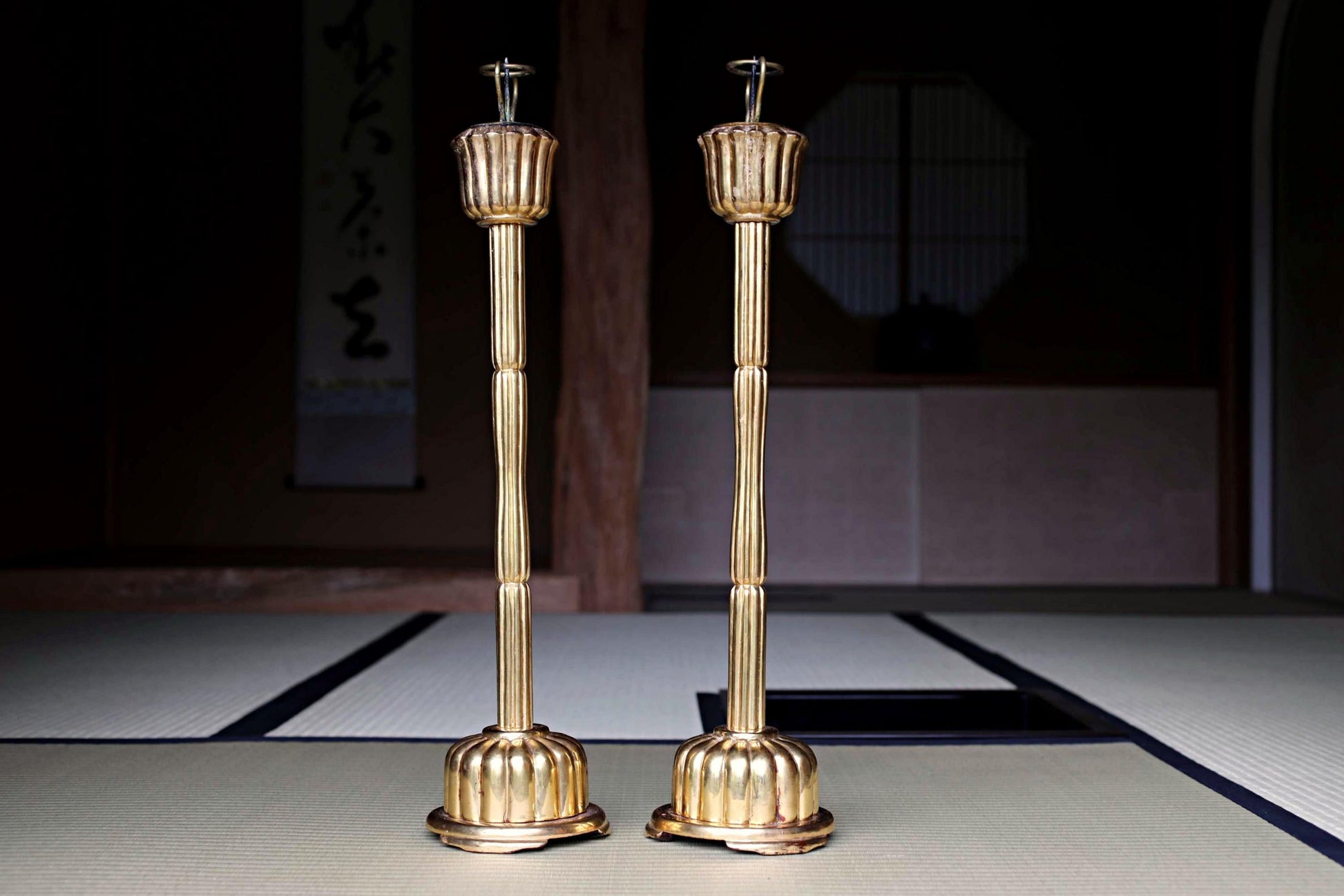 two golden candlesticks with a dark background.