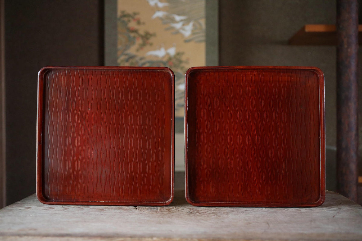 two square wooden trays with a reddish-brown finish, placed side by side on a wooden surface.