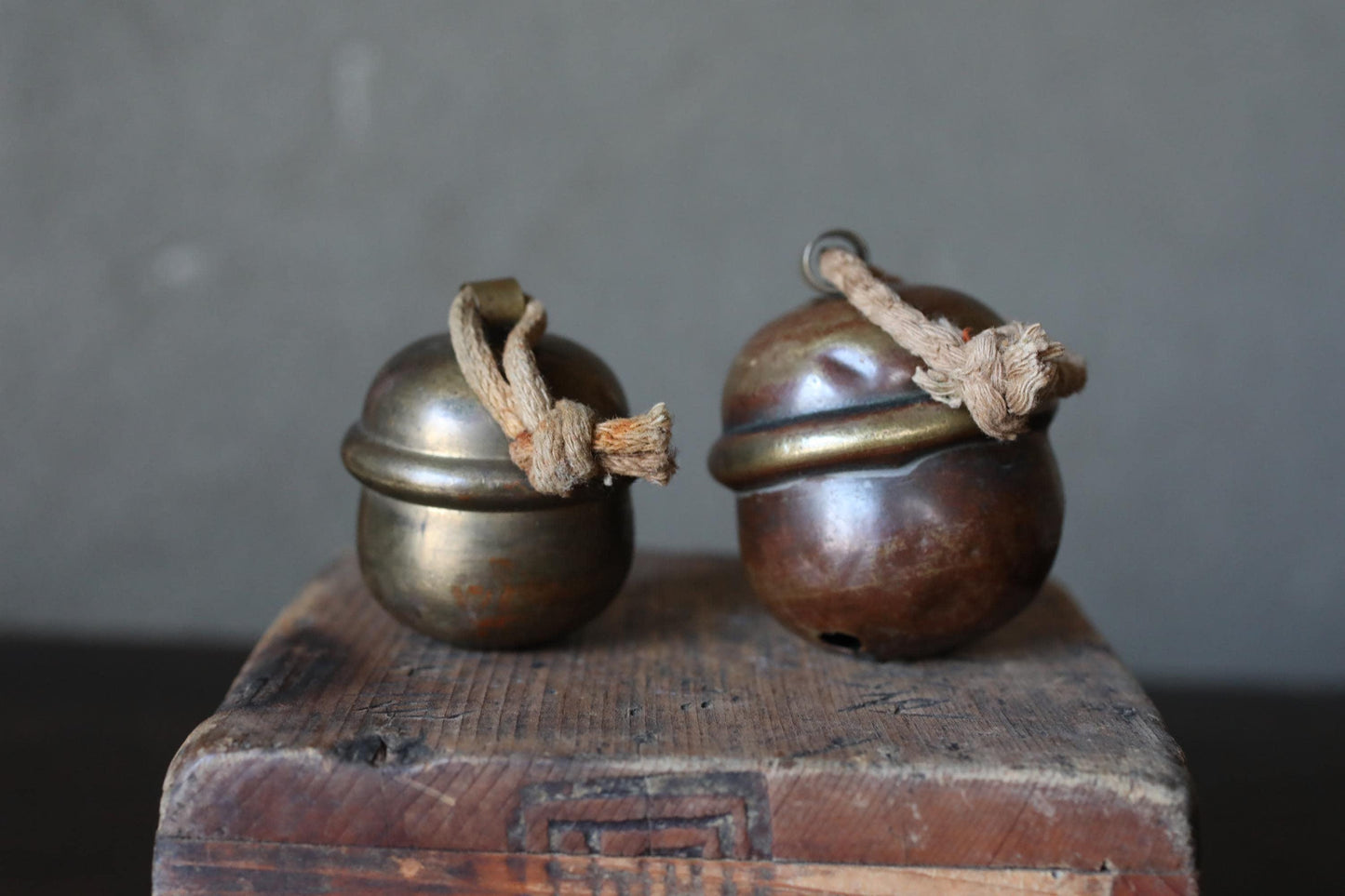 Two brass bells with wooden handles are placed on a wooden surface.