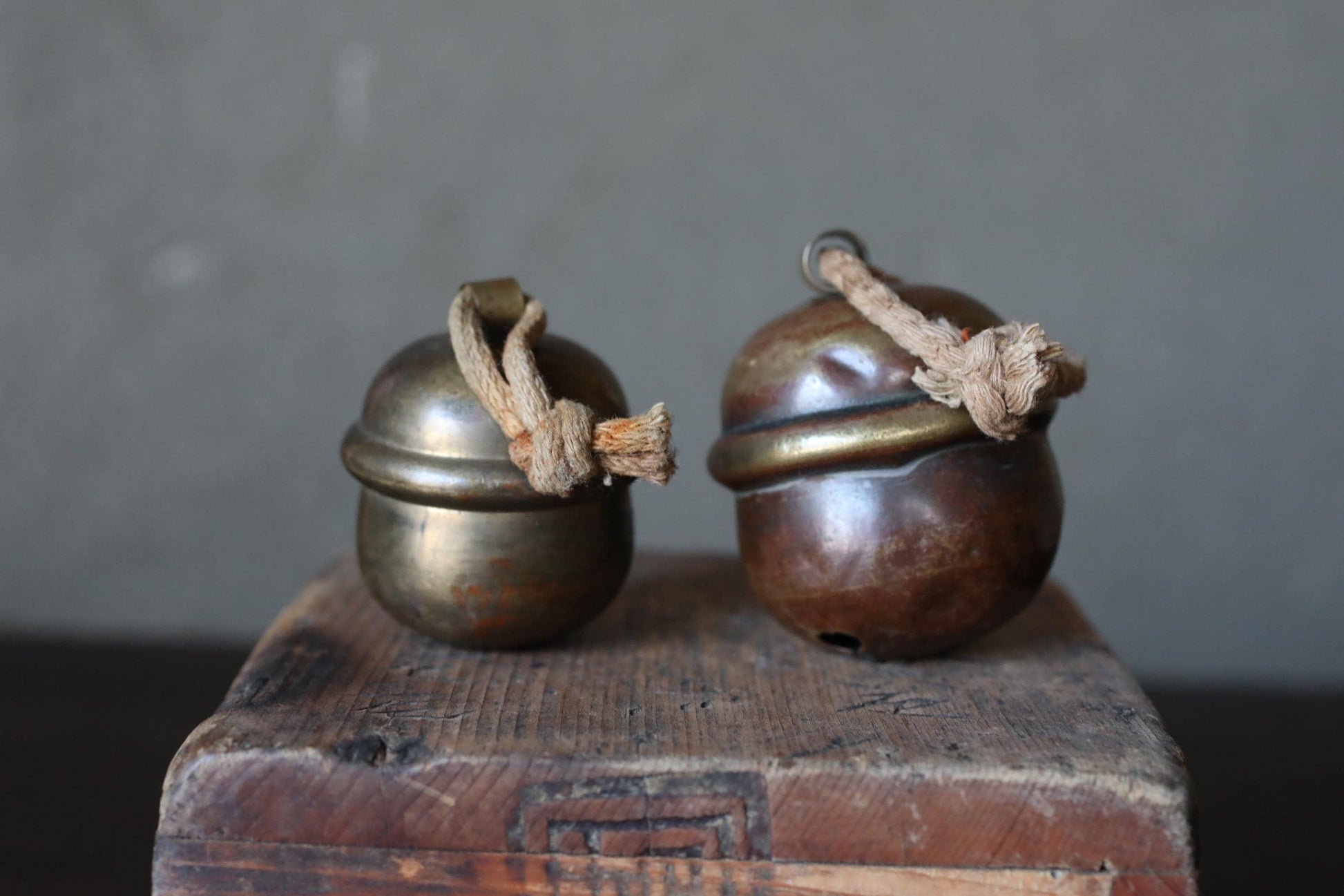Two brass bells with wooden handles are placed on a wooden surface.