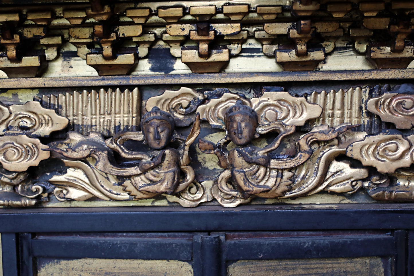 intricate, ornate, and gilded decorations with two figures, possibly representing a deity or a religious figure, on a dark background.