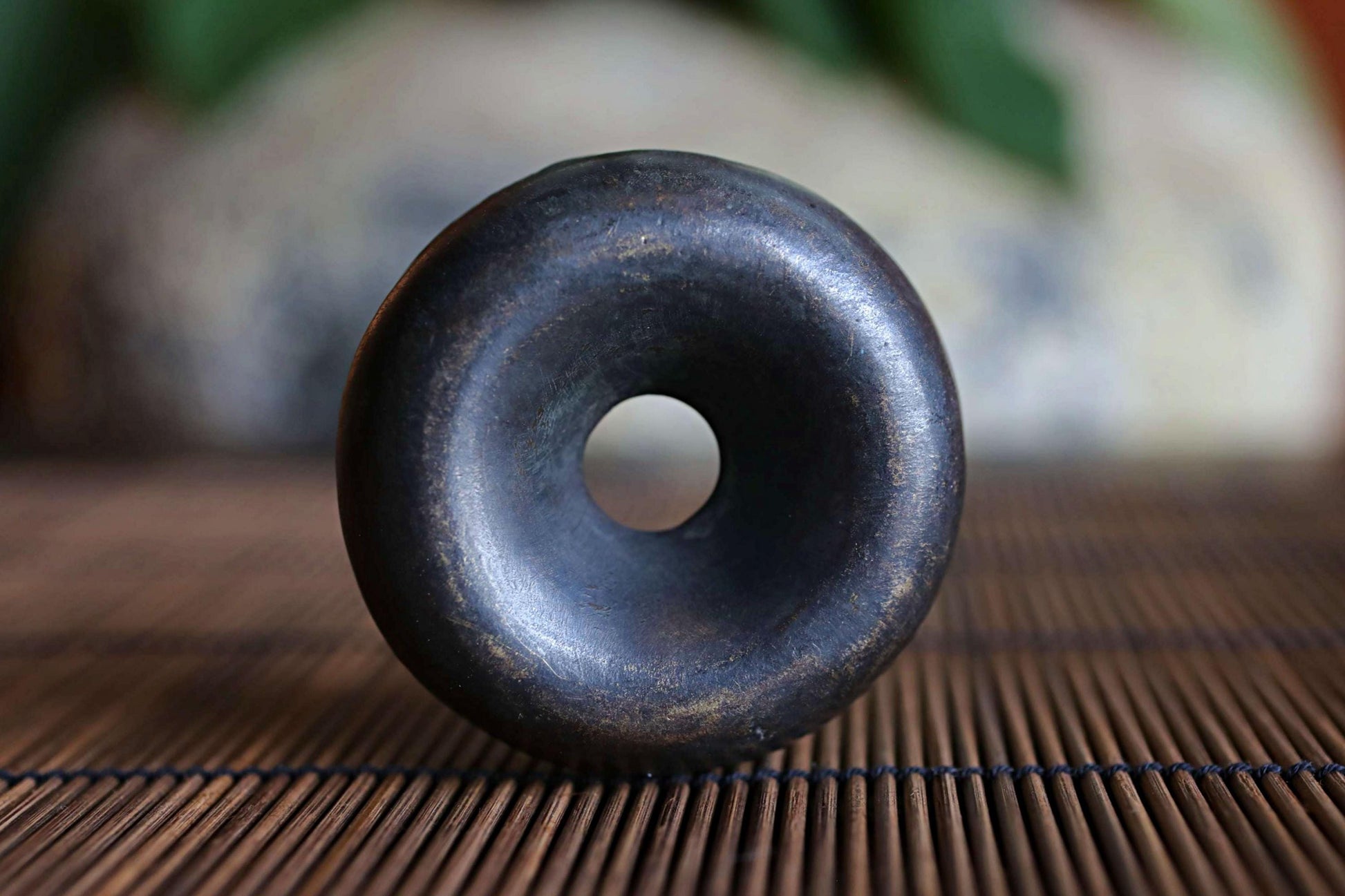A black, round object with a hole in the center is sitting on a bamboo mat.