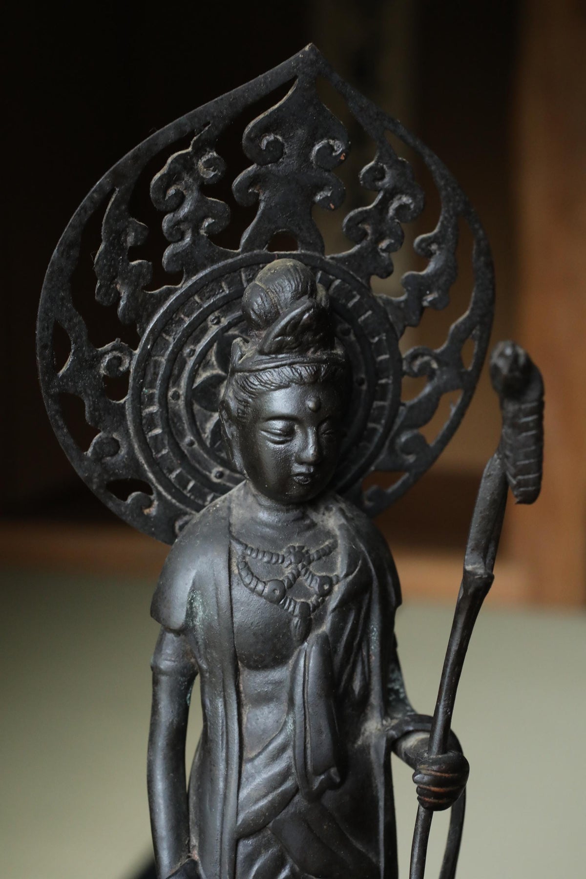 A bronze statue of a deity, possibly a Buddha, with intricate designs and patterns on its headdress.