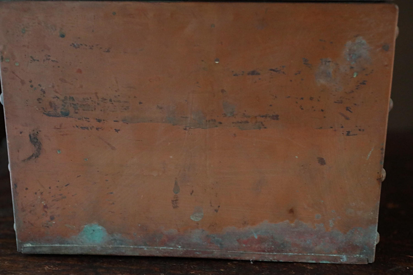 a weathered, brown metal surface with visible scratches and marks, suggesting it has been exposed to the elements for an extended period of time.