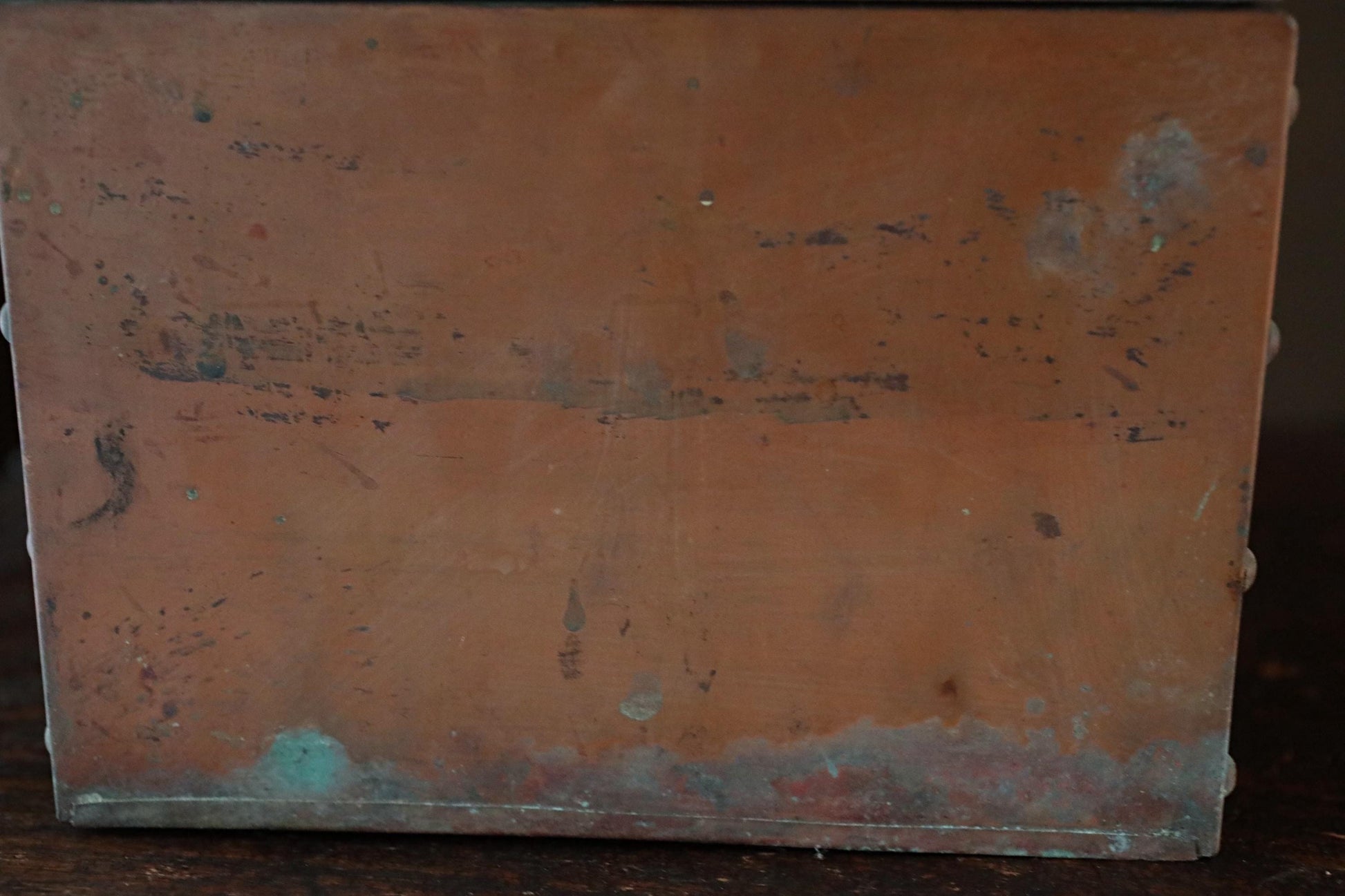a weathered, brown metal surface with visible scratches and marks, suggesting it has been exposed to the elements for an extended period of time.